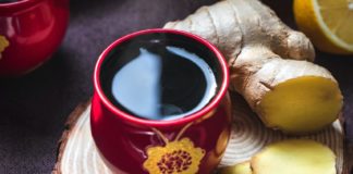 Chopped up ginger root next to a mug of tea