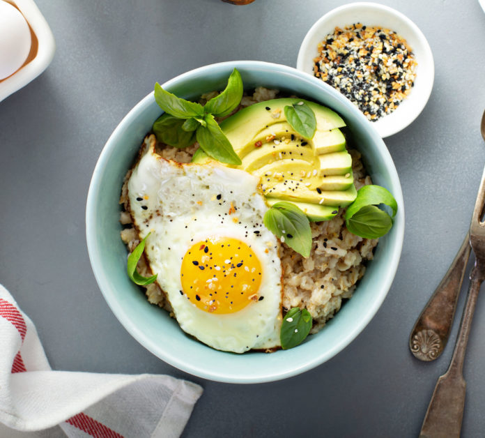 Savory oatmeal with sunny side up egg and avocado for breakfast overhead