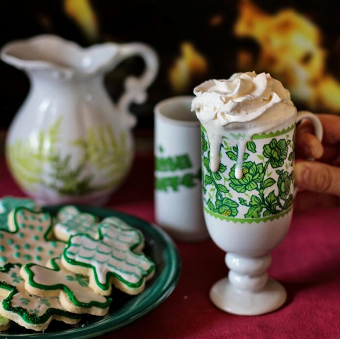 Beverage in an Irish cup beside plate of St. Patrick's Day cookies